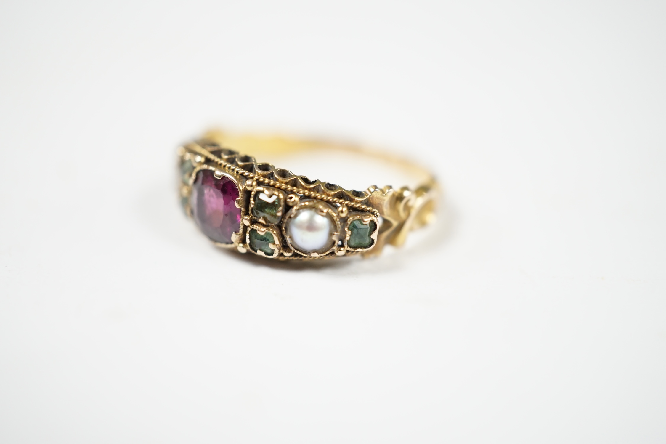 A late Victorian 15ct gold, garnet, emerald and seed pearl cluster set dress ring, in the Suffragette colours, size L/M, gross weight 2.1 grams. Condition - fair to good